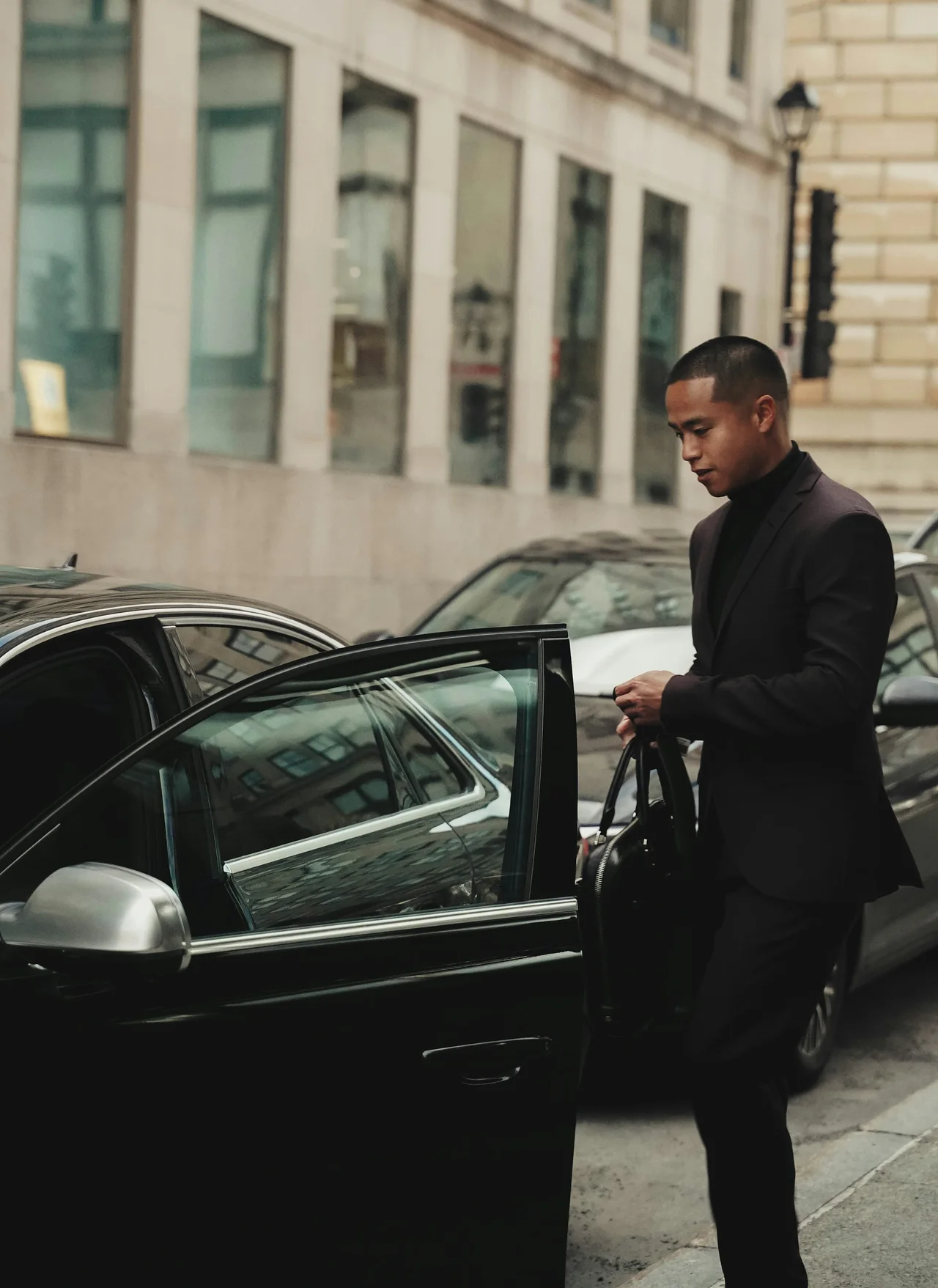 Chauffeur beside a black sedan